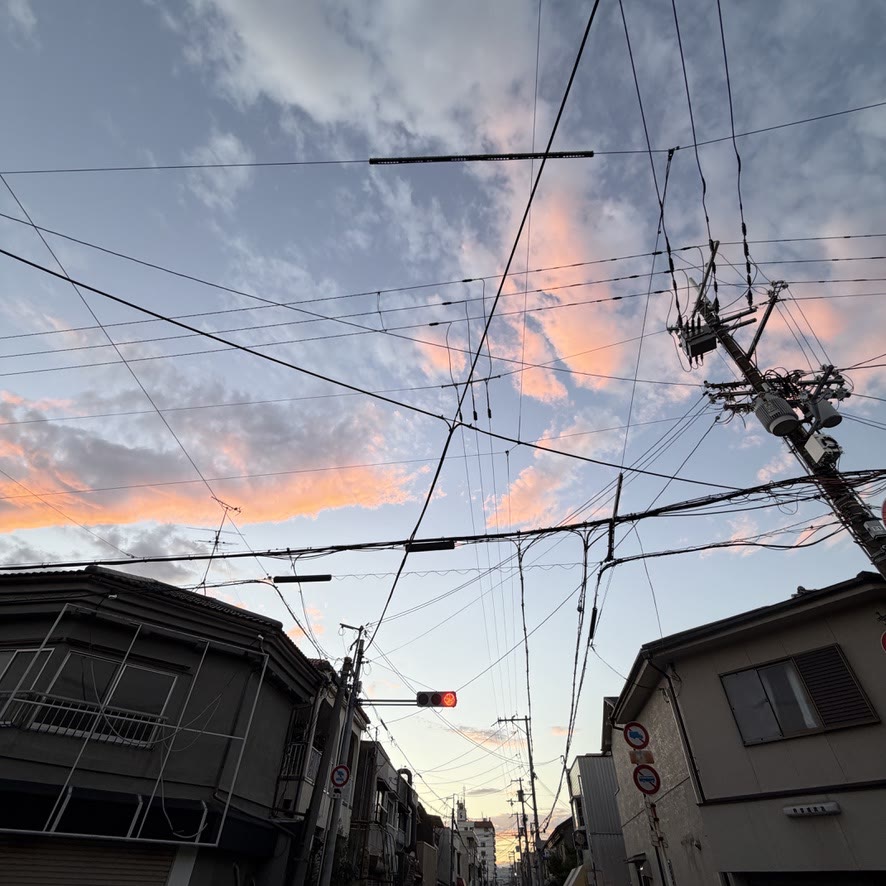 朝焼けに染まる空と電線が交差する街角